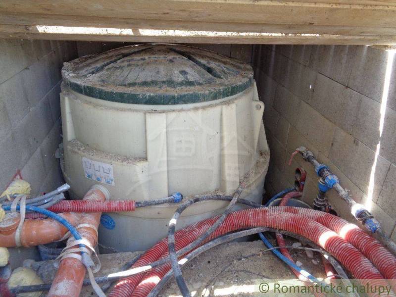 A plastic tank with pipes in the basement, the foundation of a family house.