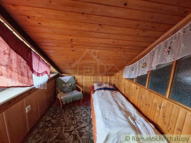 In this cozy cabin, there is a wooden room with a bed and a chair by the window.