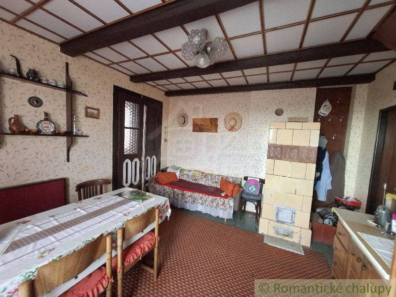 A traditional room interior with old furniture, paintings, and a ceramic stove in a cottage.