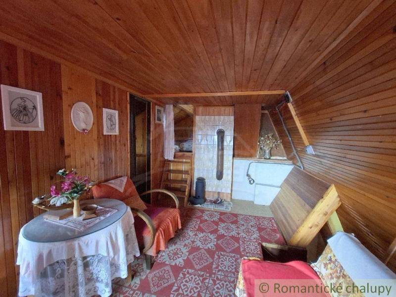 A cottage with wooden cladding, a tiled stove, and flowers on the table. A romantic cottage.