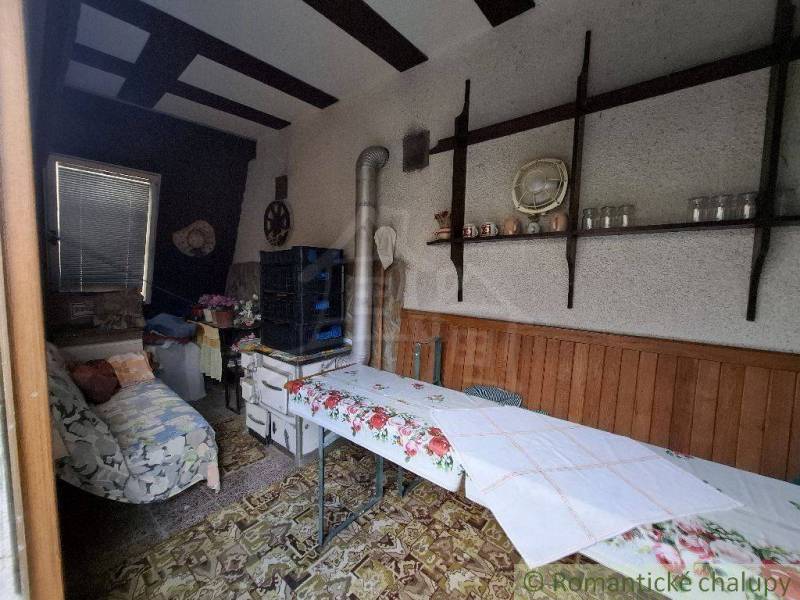 A room in a cottage with a floral tablecloth and retro decorations on a wooden shelf.