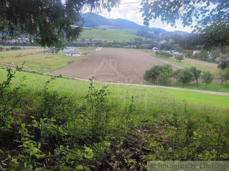 Vast fields, picturesque landscape, mountains in the distance, and greenery of gardens in the foreground.