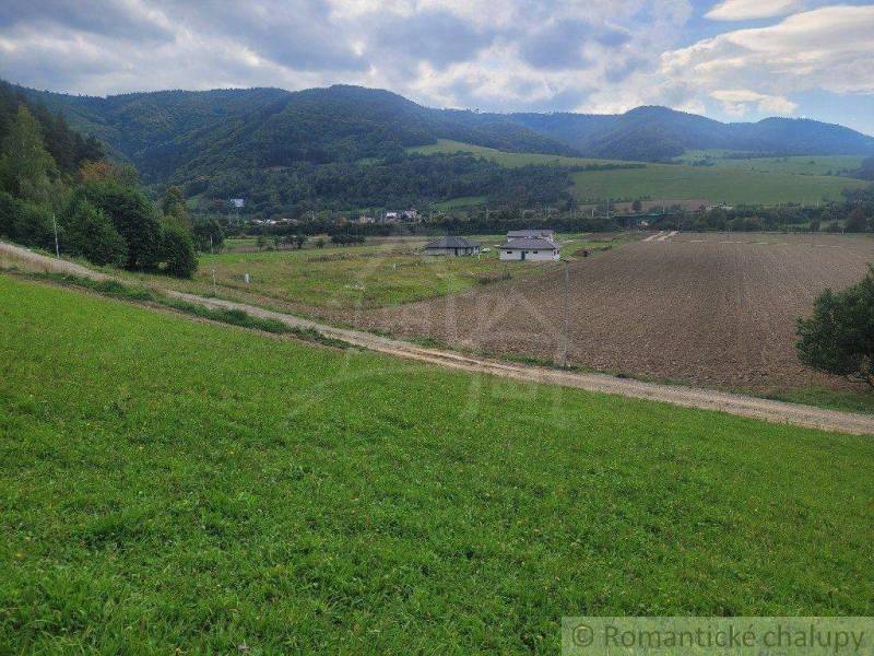 Countryside landscape, meadow, roads and gardens under mountains and clouds in the sky.