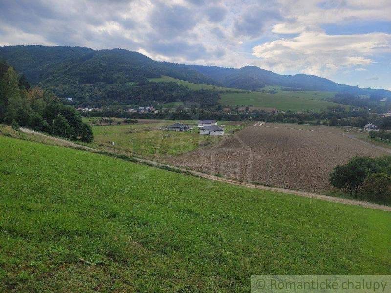 A beautiful landscape with fields and gardens, surrounded by green hills and a village.