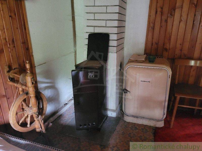 In the room of a family house, an antique spinning wheel, a stove, and a historical refrigerator by the wall.