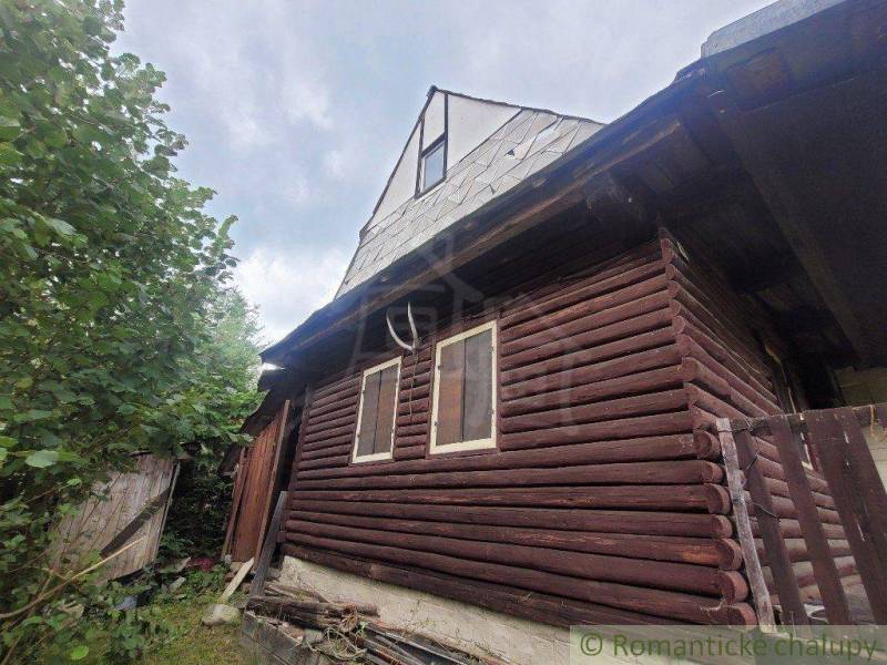 A wooden cottage with a wooden fence and shutters, set in green nature. Family house.