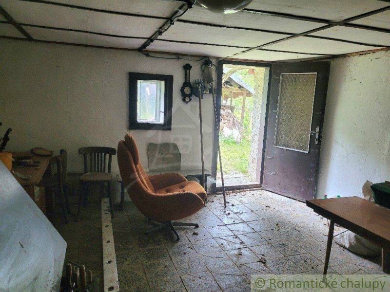 The interior of a family house with an old armchair, open doors, and a rustic appearance.