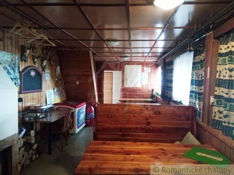 The interior of a wooden cabin with benches and a map, immersed in a rural setting.