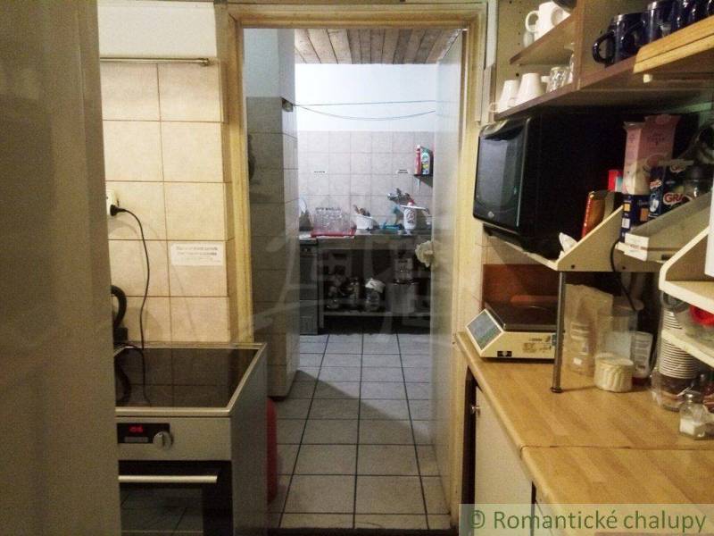 A kitchen in a cottage, wooden shelves, stove, kitchen equipment. Romantic cottage atmosphere.