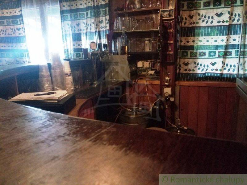 Interior of the cabin, wooden paneling, window curtains, drinks, and shelves with glasses.