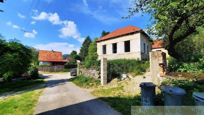 A nice family house for renovation, surrounded by trees, road, trash bins.