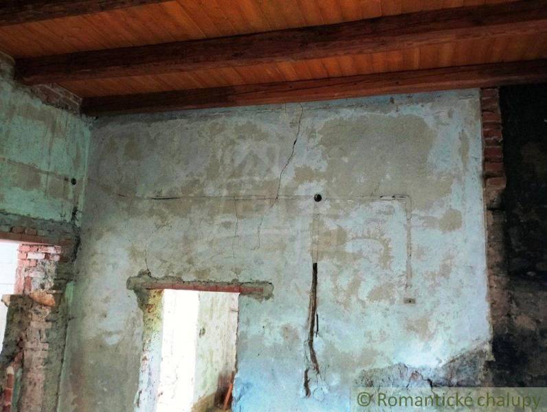 The worn plaster in the old family house, cracks on the walls, and a ceiling made of beams.