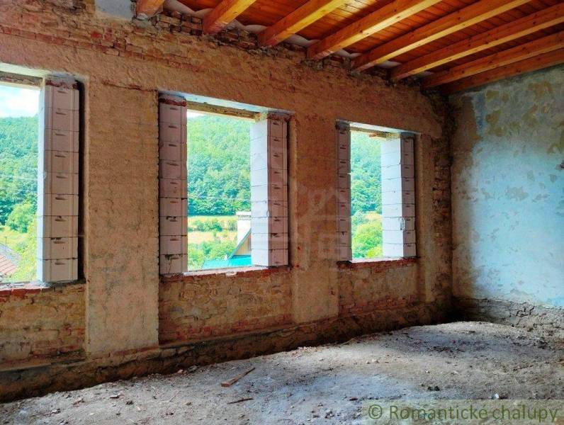 Interior of a building with brick walls, a wooden ceiling, and a view of nature.