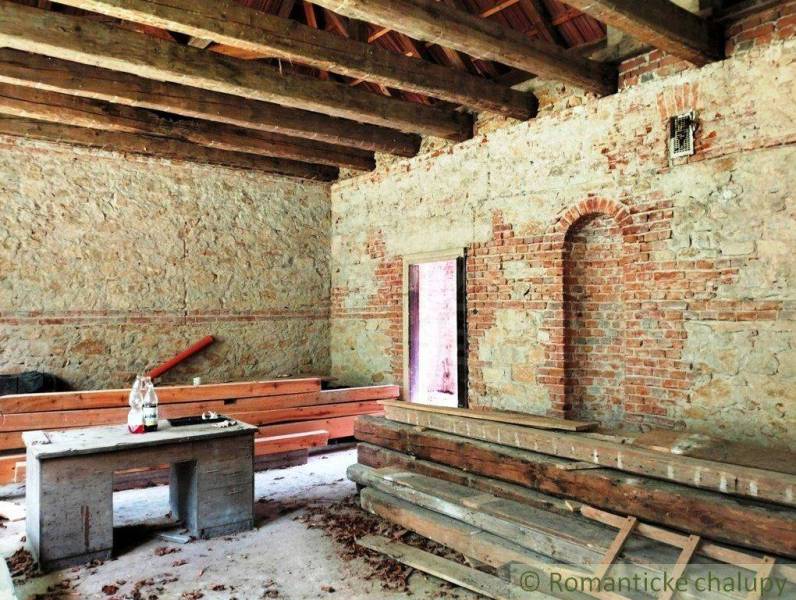 The interior of an old family house with raw walls and a beamed ceiling, ready for renovation.