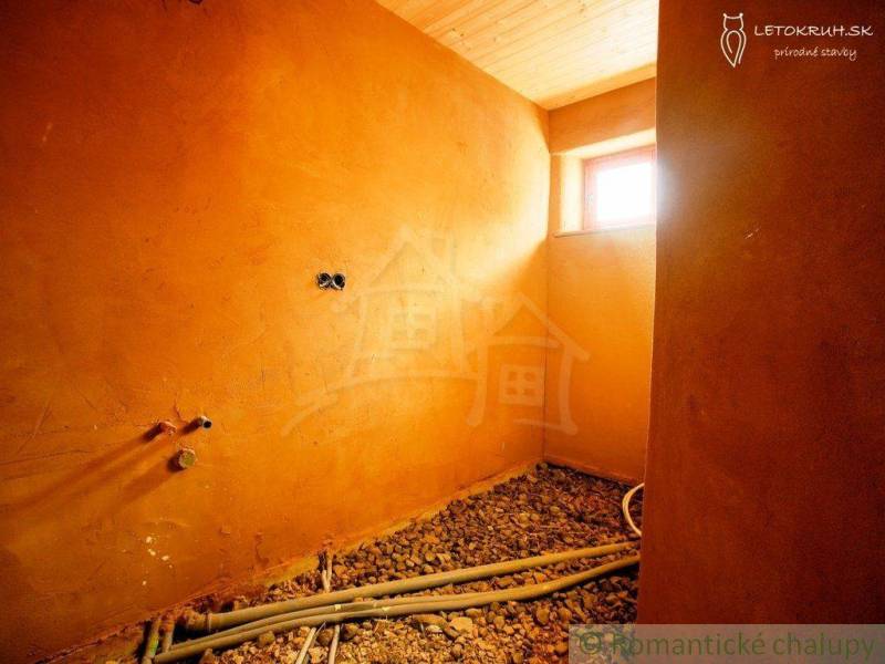 Interior of a family house with clay walls, a wooden ceiling, and preparation for installations.