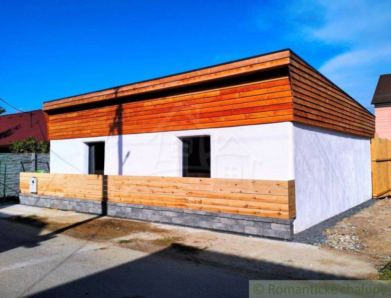 A family house with wooden cladding and a white facade on a quiet street.