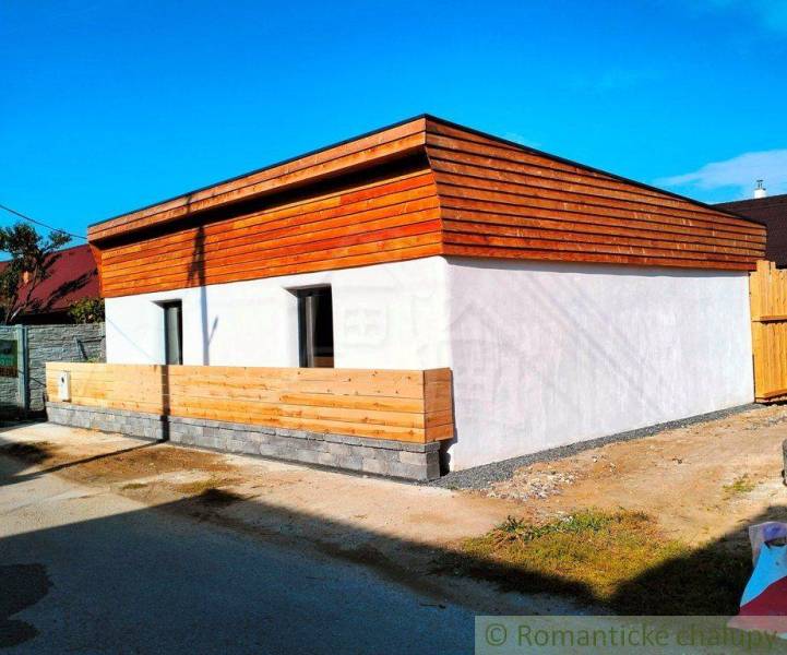 Family house with wooden cladding on the facade, fencing combined with concrete.