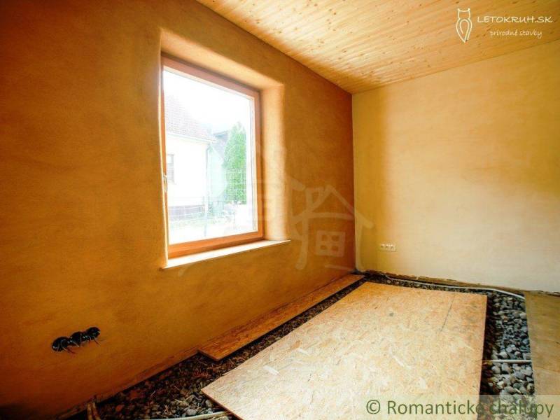 Interior of a country house with a clay wall and a wooden ceiling.