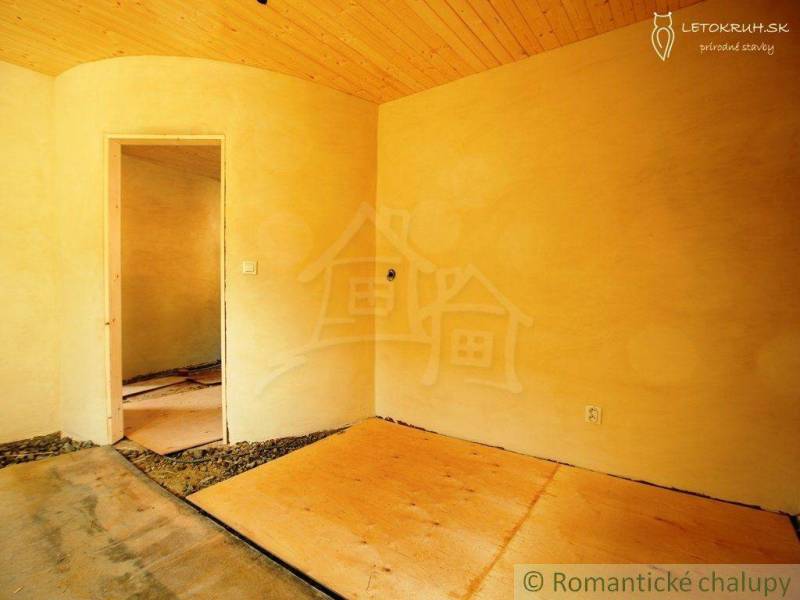 Rooms of a family house with a wooden ceiling and clay walls without flooring.