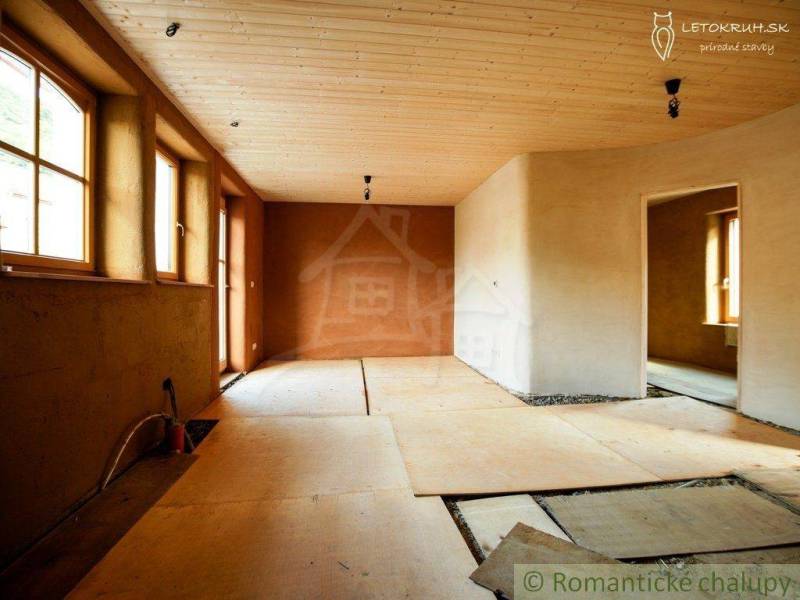Family house with a wooden ceiling and clay plaster, large windows for natural light.