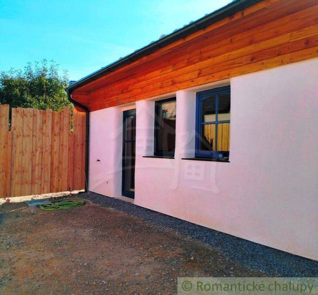 A family house with wooden cladding, featuring blue windows and a gate.