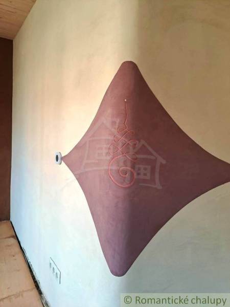 On the wall of the family house, there is a clay decoration with an elegant ornament and a stream of light.