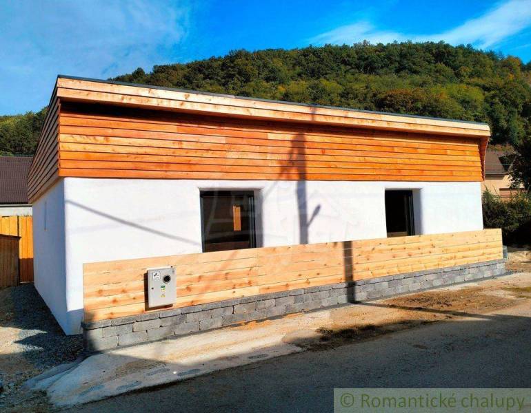 A family house with wooden elements on the facade surrounded by a natural environment and a blue sky.