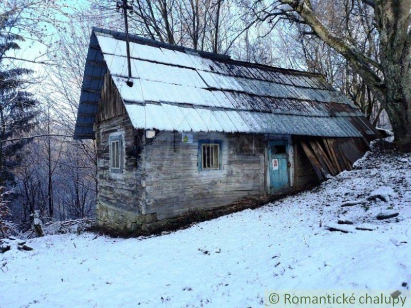 A wooden cabin in a snowy landscape hidden among trees, ideal for a romantic getaway.