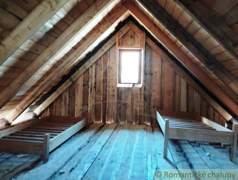 Attic cabin, wooden walls and ceilings, simple beds, cozy space for relaxation.