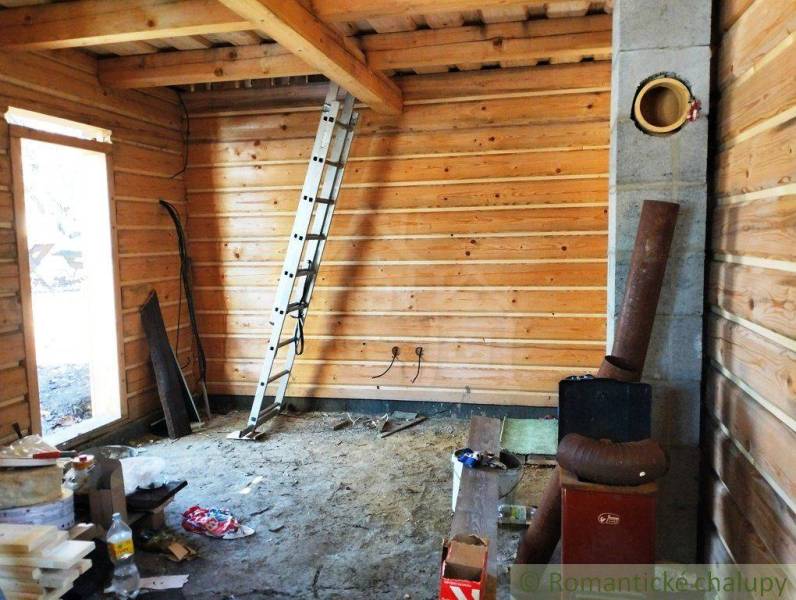 Attic cabin with wooden interior, ladder, and building materials in the room.