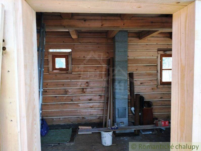The interior of a wooden cabin with a brick chimney and wooden floor in the countryside.