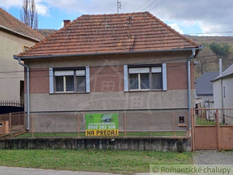 Older family house with a red roof for sale in a quiet village setting.