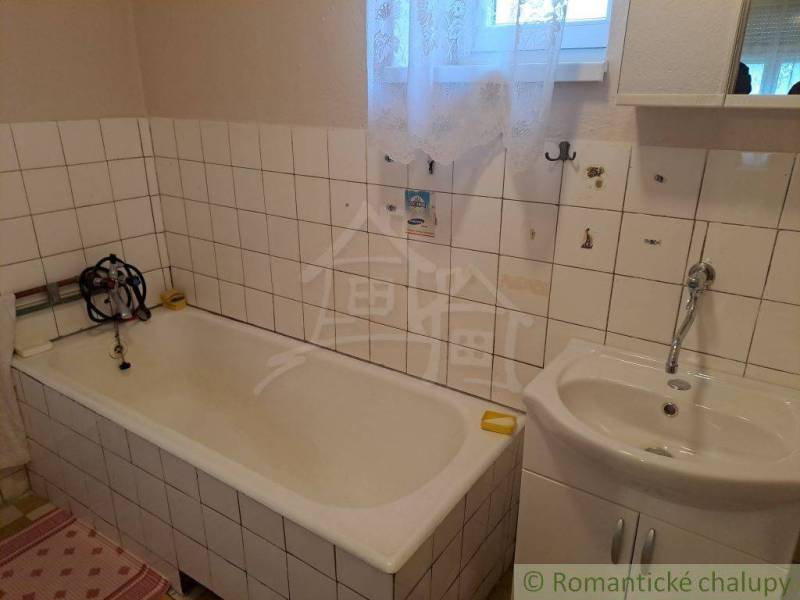 The bathroom contains a bathtub and a sink with tiles in a family house.