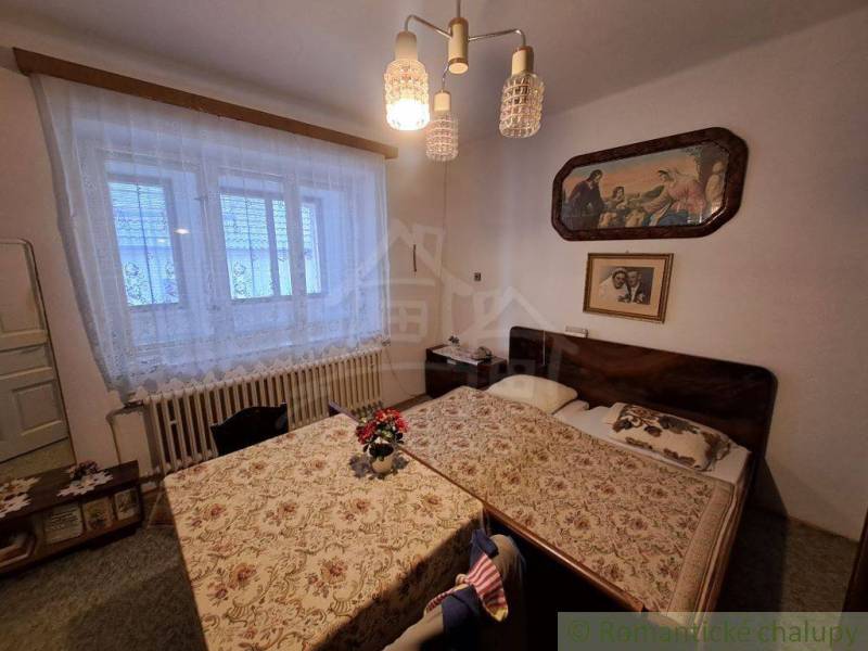 A bedroom in a family house with two beds, paintings, and a decorative chandelier.