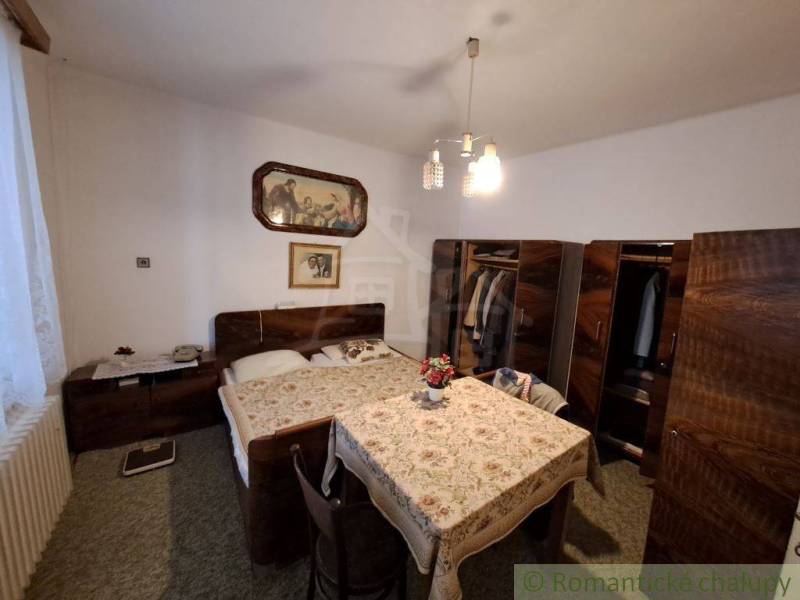 A bedroom with wooden furniture, a bed, and flowers in a family house creates a cozy atmosphere.
