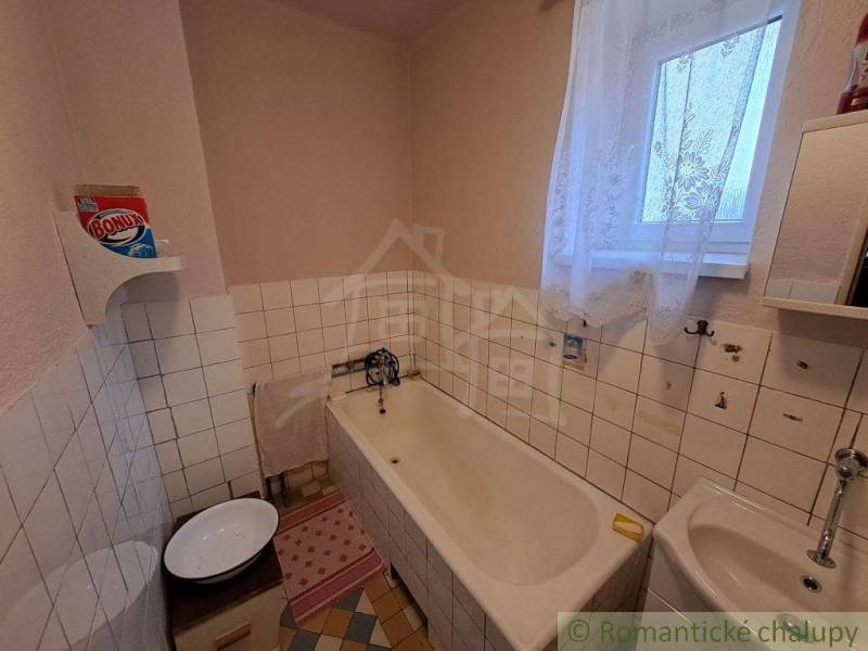 Family house bathroom with a bathtub, sink, window, and patterned floor.
