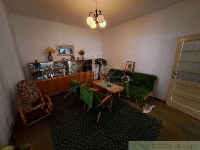 Living room in a family house, contains an old display cabinet, a sofa, and a carpet.