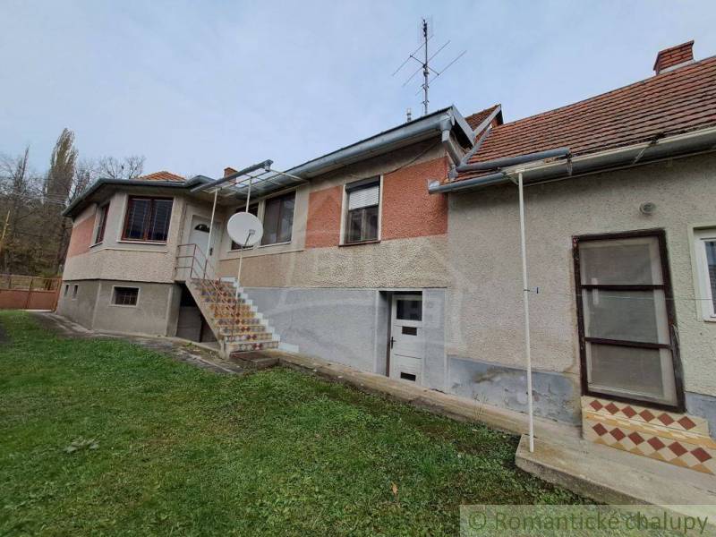 A family house with a red roof has a satellite dish installed on the facade.