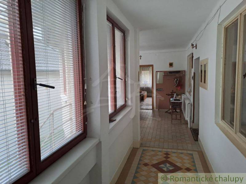 Family house with a hallway equipped with windows with blinds and tiles.