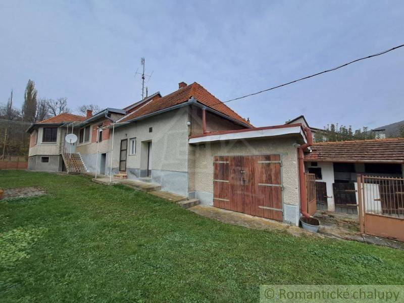 A family house with a gable roof, garage, and garden in a peaceful village setting.