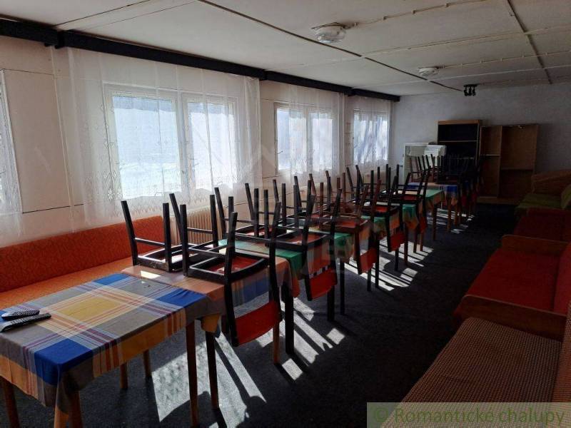 Interior with commercial spaces, tables and chairs overturned on colorful tablecloths.