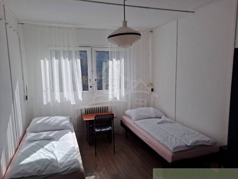 The room contains two beds, a table, a chair, and curtains.