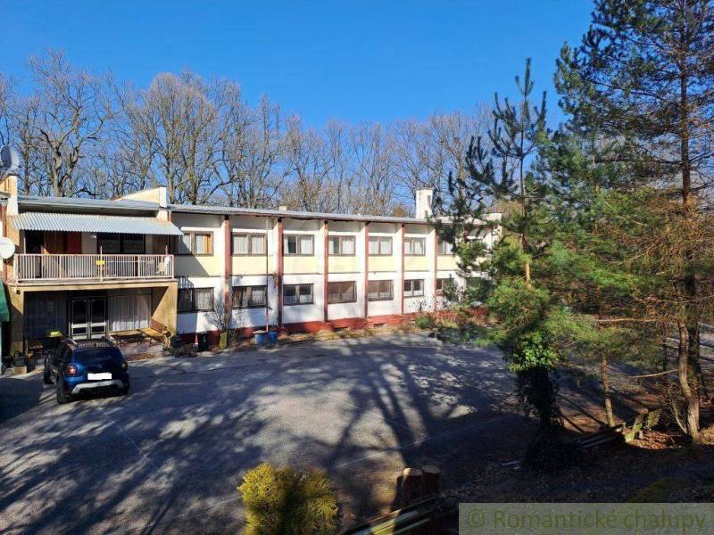 A residential building surrounded by trees and parking spaces, suitable for commercial premises.
