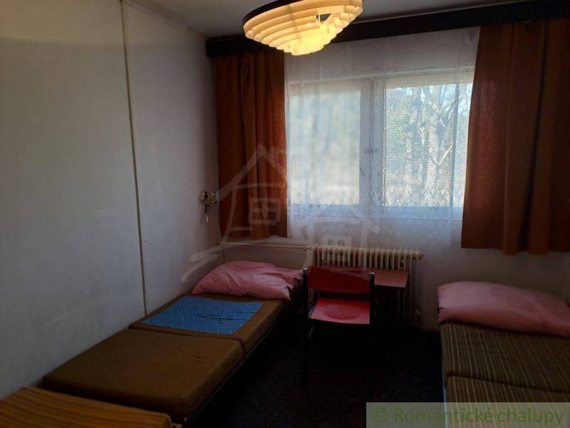 A room with beds, curtains, and a table, ideal for simple commercial spaces.