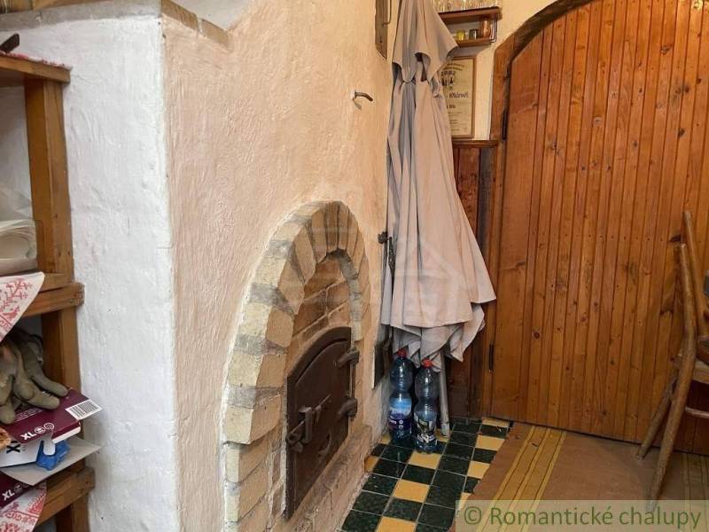 Traditional brick oven, wooden shelves with items, rustic cottage awaits discovery.