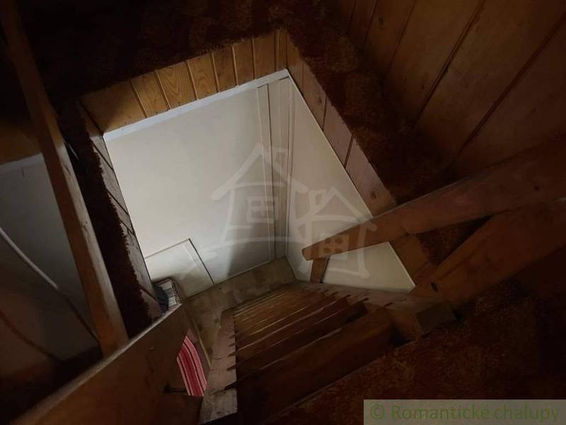 Wooden stairs to the attic in the cottage, with a wooden paneled wall.