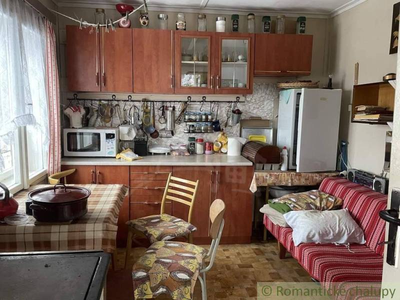 We see a kitchen with a wooden kitchen unit in a cabin, with a dining table.