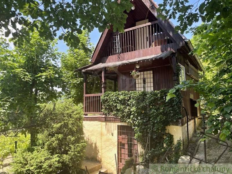 A cottage in Jablonov nad Turňou surrounded by greenery, with a wooden balcony and climbing plants.