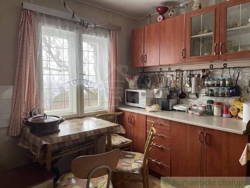 Kitchen in the **cottage**: dining table, chairs, kitchen unit, utensils, sink, containers on the window.