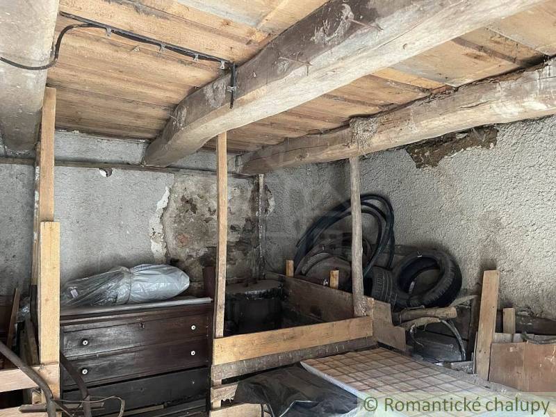 An old attic space contains furniture, a wooden structure, and electrical wiring of a family house.